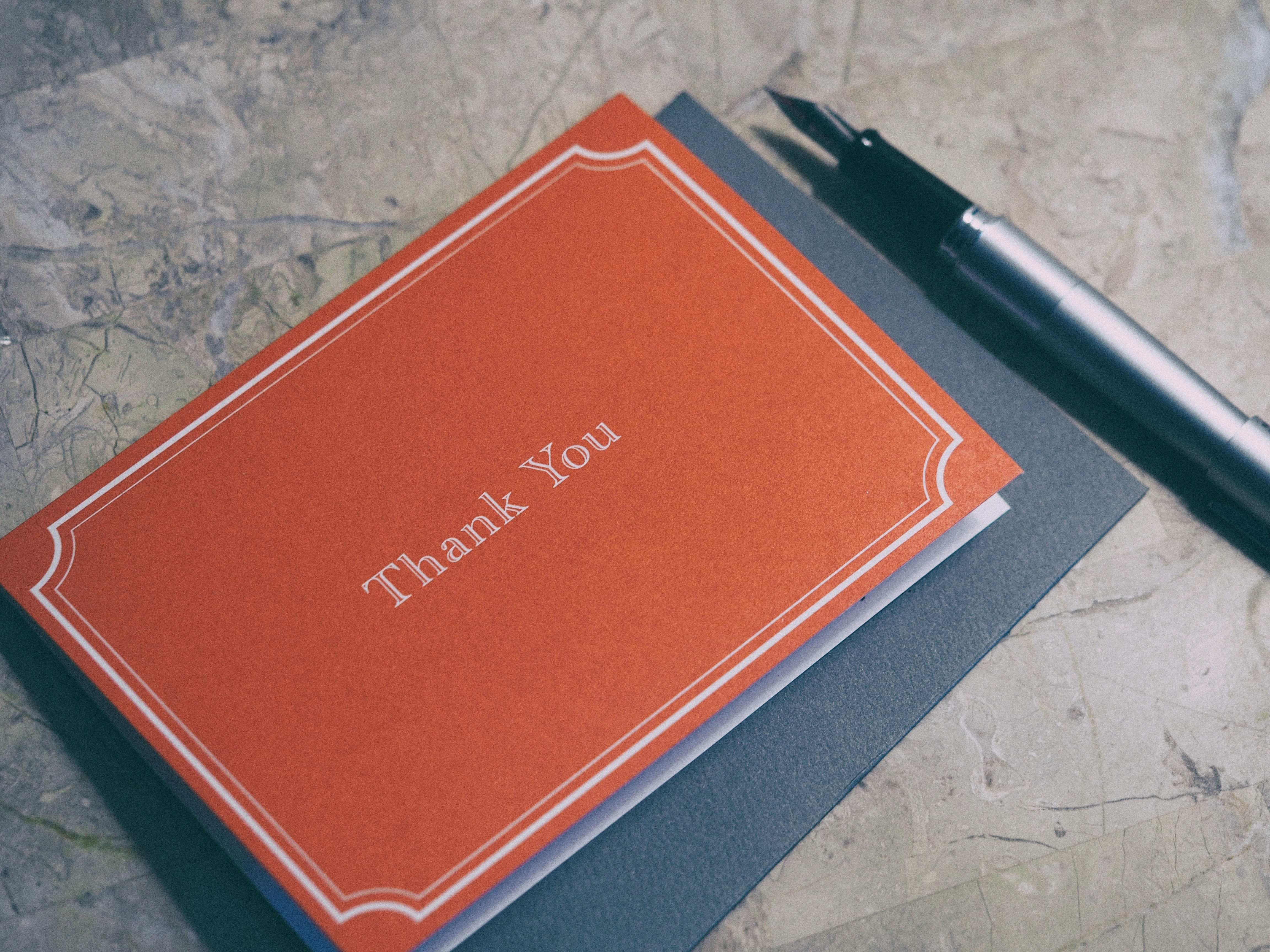 A fountain pen next to a “Thank You” card